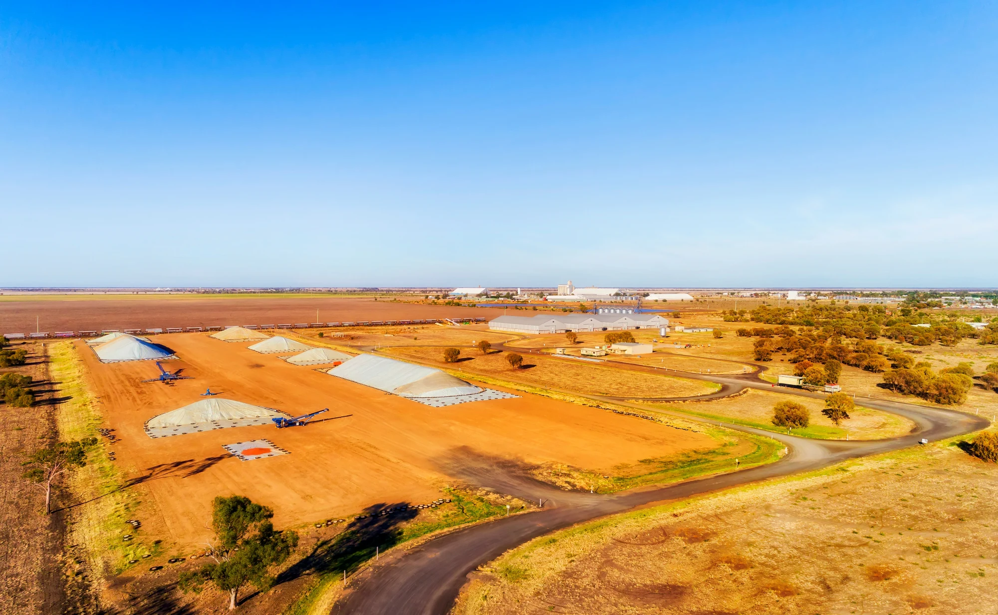 Aerial view of grain silos and storage bunkers beside a rural roadway