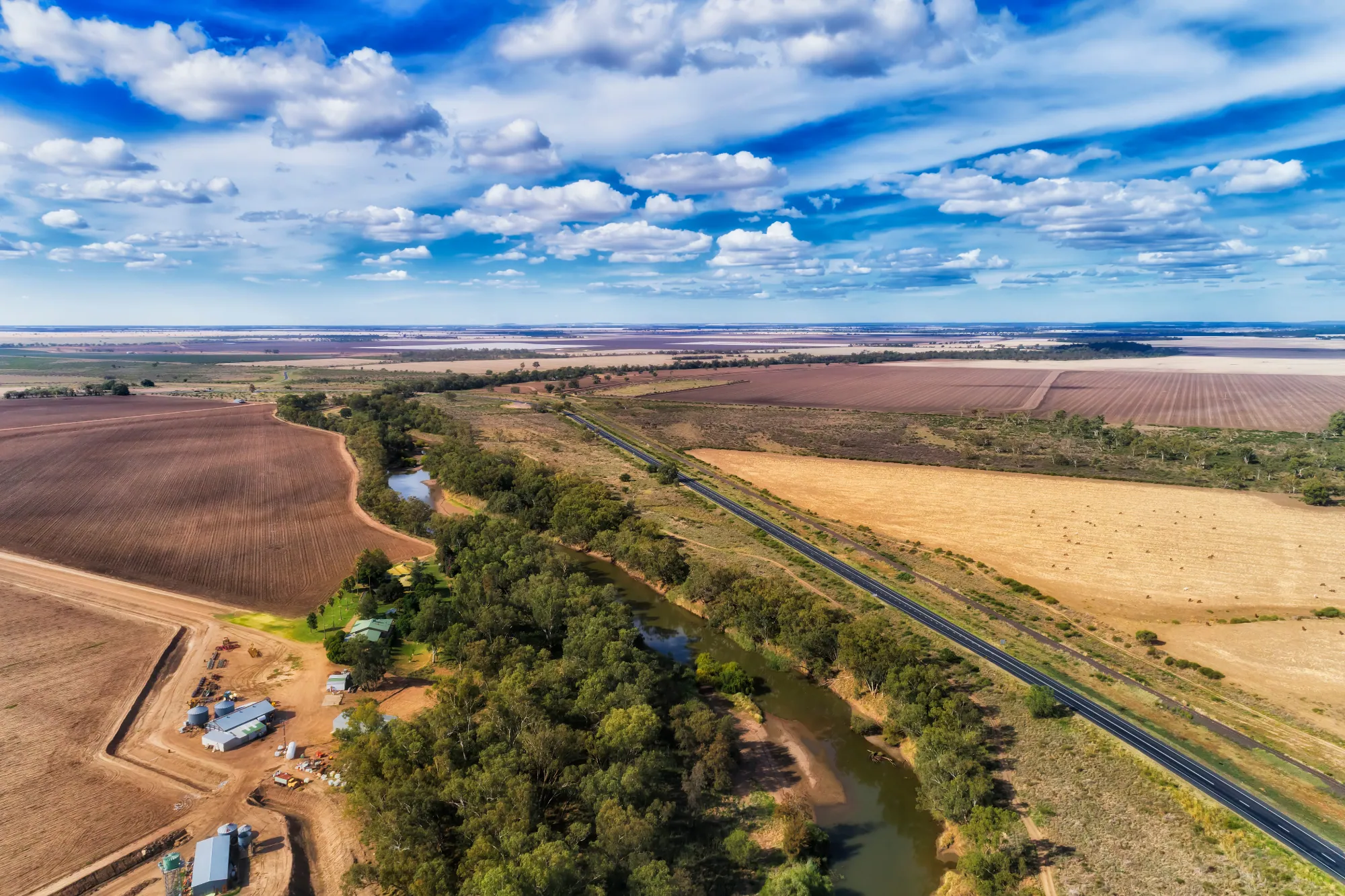 Aerial view of a river winding through farmland beside a highway