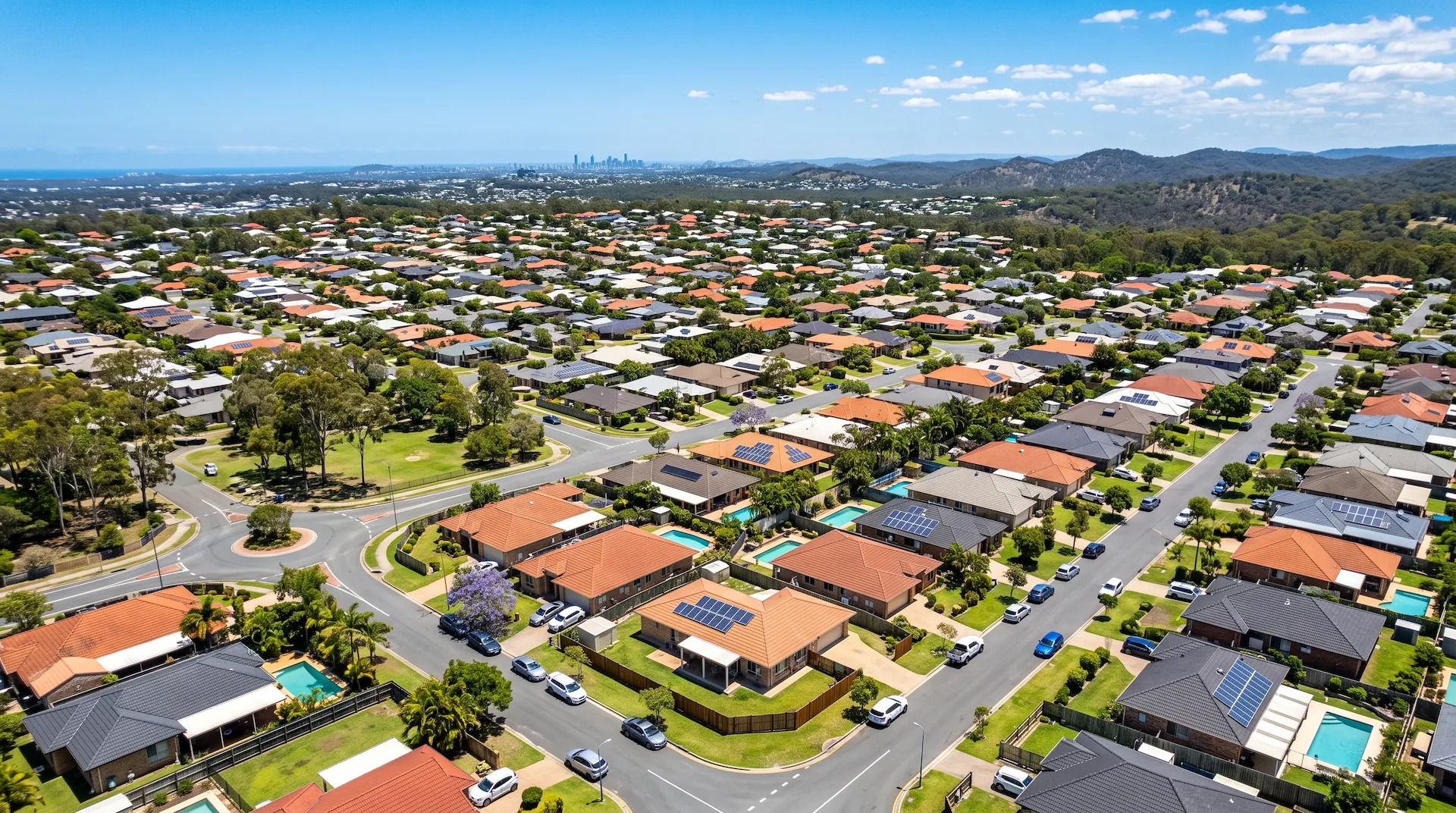 Aerial view of a suburban estate with pools, solar panels and coastline