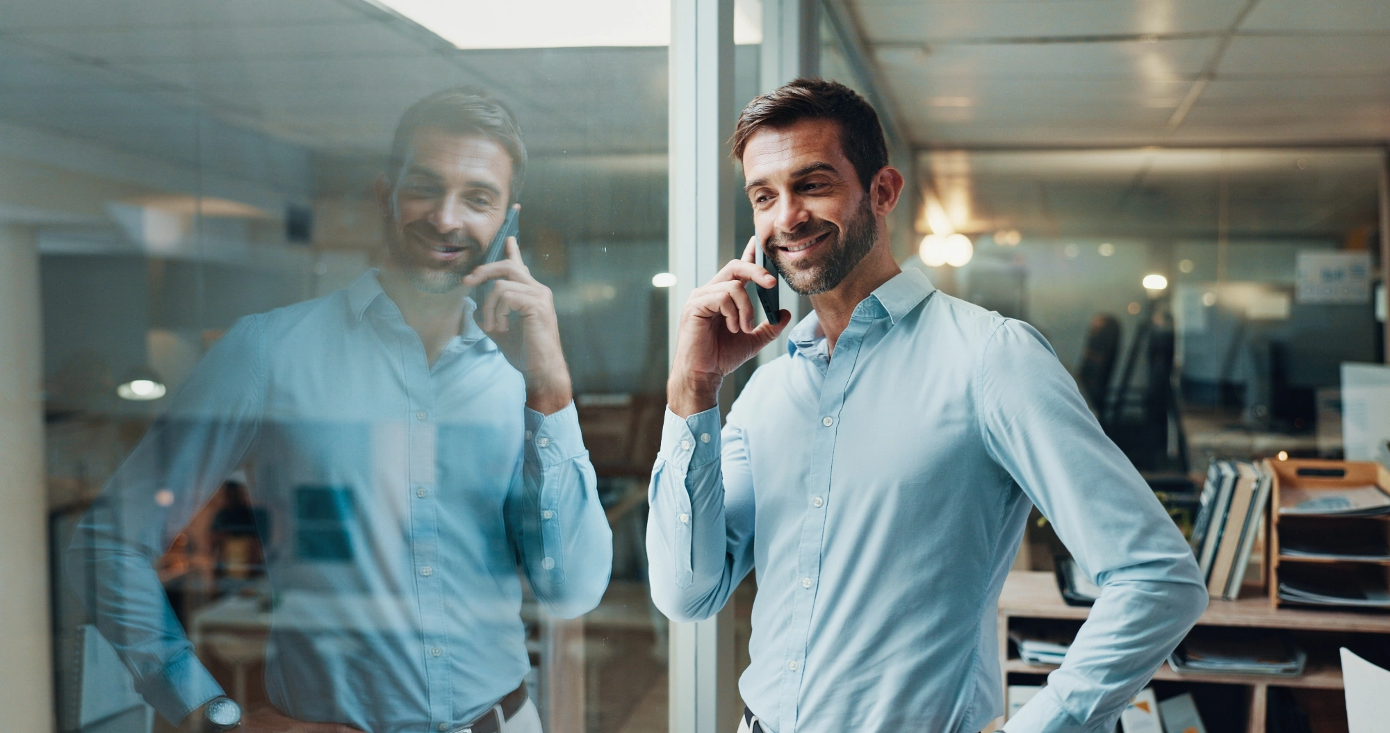 Man in a light blue shirt smiling while talking on his phone